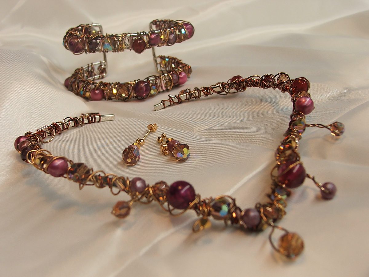 Wire-wrapped copper and plum cuff, necklace and earrings on satin